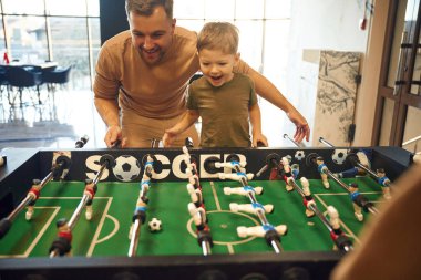 Eğlence anlayışı. Baba ve oğul içeride masa futbolu oynuyorlar..