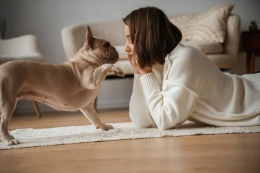 Yan taraftan bak, yere uzan. Genç kadın köpeğiyle evde..