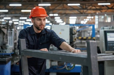 Makinelerle çalışmak. Fabrika işçisi kasketli bir şekilde içeride..