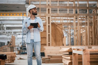 Bitmemiş proje, elinde dijital tablet var. Ahşap depoda sanayi işçisi..