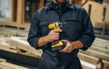 Küçük bir matkap. Erkek müteahhit ahşap ev inşaatında..