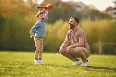 Hafta sonu aktiviteleri. Oyuncak uçakla oynamak. Mutlu baba ve oğul yazın sahada eğleniyorlar..