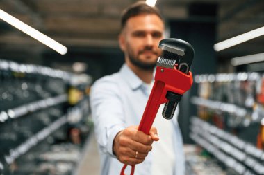 Kırmızı boru anahtarı. Adam hırdavatçıda..