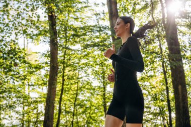 Koşmak, ormanda koşmak. Genç, sıska kadın dışarıda siyah spor kıyafetleri giyiyor..