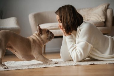Yan taraftan bak, yere uzan. Genç kadın köpeğiyle evde..