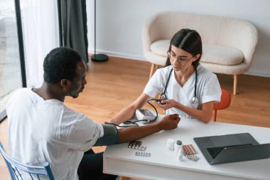 Kadın doktor bir erkeğin kan basıncını ölçer..