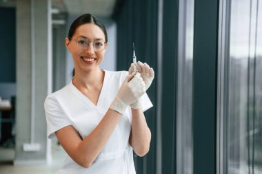 Şırınga ellerinde. Beyaz önlüklü kadın doktor içeride..