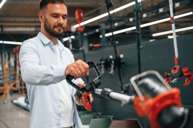 Çim biçme makinesi ellerinde. Adam hırdavatçıda..