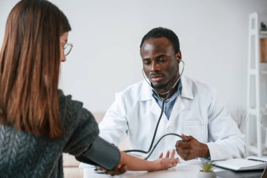 Müşteri hizmetleri. Bir doktor genç bir kadının kan basıncını ölçer..