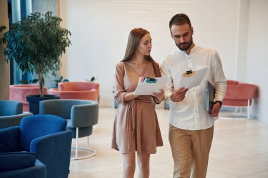 Elinde belgelerle ileri doğru yürüyorsun. Erkek ve kadın işe gitmek üzere yola çıktılar..