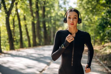 Odaklanma, koşma, koşma. Genç, sıska kadın dışarıda siyah spor kıyafetleri giyiyor..