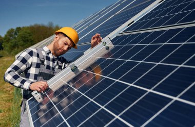 Dengeleyiciyi kullanarak. Gündüz vakti fotovoltaik güneş panelleri olan bir mühendis..