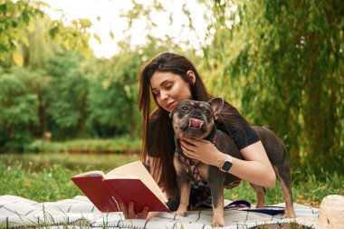 Kırmızı defter, çimlerin üzerinde. Genç güzel bayan köpeğiyle birlikte parkta..