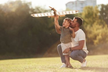 Mutlu yüz ifadesi, eğlenceli. Baba ve oğul oyuncak uçakla sahadalar..