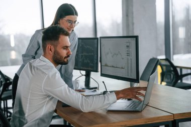 Dizüstü bilgisayarla. İki çalışan ofiste birlikte çalışıyor..