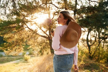 Doğada bir buket çiçekle bir kadın..