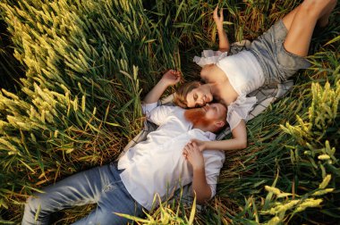 Dinleniyor, uzanıyor, yukarıdan bakıyor. Güzel bir çift yeşil tarlada birlikte..