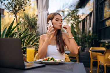 Modern akıllı telefon, masanın yanında. Güzel genç bayan restoranın dışında..