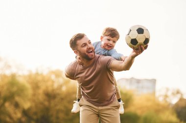 Gerçek futbol, futbol topu. Mutlu baba ve oğul yazın sahada eğleniyorlar..