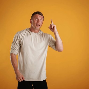 Yukarı bak, işaret et, boşluğu kopyala. Adam stüdyoda arka plana karşı..