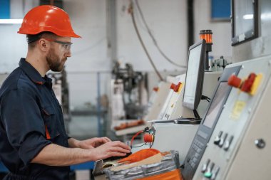 Yan görüş, makineyi çalıştırmak. Fabrika işçisi kasketli bir şekilde içeride..