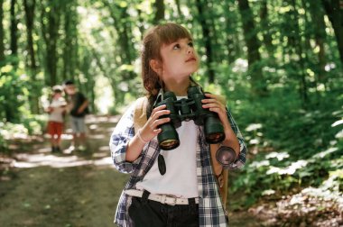 Dürbün ellerinde. Çocuklar yazın gündüz vakti ormanda..