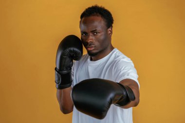 Güç kavramı. Boks eldivenleriyle. Siyah adam sarı arka plana karşı..