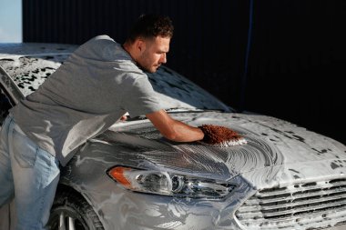 Otomobili yıkama işlemi. Adam dışarıda arabasıyla bekliyor..