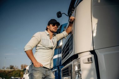 Ön manzara, kabine yaslanma. Kamyon şoförü açık havada nakliye aracının yanında..