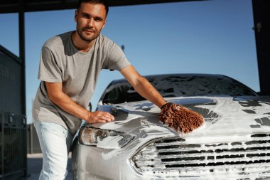 Beyaz temizlik kimyasalı, otomobili yıkamak. Adam dışarıda arabasıyla bekliyor..