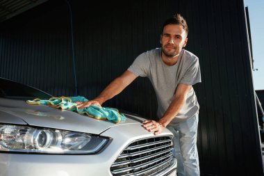 Ellerinde bezle. Adam dışarıda otomobille dolaşıyor..