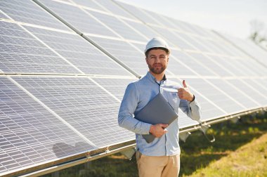 Dizüstü bilgisayarla. Gündüz vakti fotovoltaik güneş panelleri olan bir mühendis..