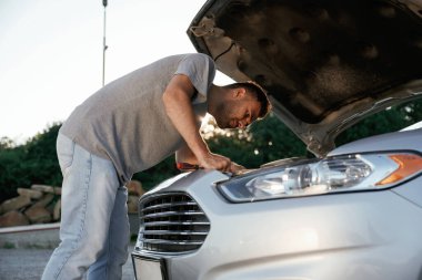 Bozuldu, kaput açıldı, tamir ediliyor. Adam dışarıda arabasıyla bekliyor..
