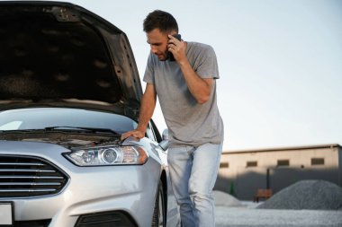 Kaza, bozuk otomobil park halinde. Adam dışarıda arabasıyla bekliyor..