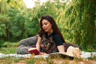Kırmızı defter, çimlerin üzerinde. Genç güzel bayan köpeğiyle birlikte parkta..