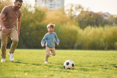 Futbol oynamayı öğreniyorum. Mutlu baba ve oğul yazın sahada eğleniyorlar..