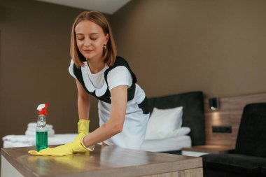 Masayı temizliyorum. Genç oda hizmetçisi otel odasında..