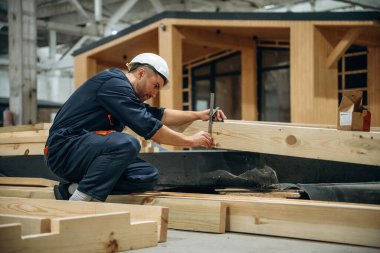 Tahtaları ölçüyorum. Erkek müteahhit ahşap ev inşaatında..