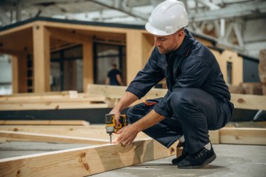 Küçük bir matkap. Erkek müteahhit ahşap ev inşaatında..