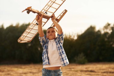 Çocuk dışarıda tahta oyuncak uçakla oynuyor..