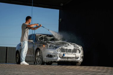 Köpük yıkılıyor, otomobil sabun içinde. Adam dışarıda arabasıyla bekliyor..