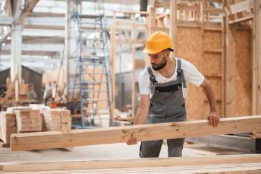 Tahtayı taşıyorum. Ahşap depoda sanayi işçisi..