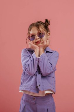 Şık güneş gözlükleriyle. Şirin küçük kız pembe arka plana karşı..