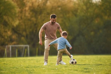 Futbol oynamayı öğreniyorum. Mutlu baba ve oğul yazın sahada eğleniyorlar..
