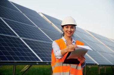 Üniformalı kadın işçi mühendisi güneş panellerinin yakınında..