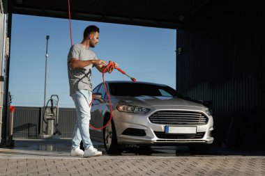 Yüksek basınç, otomobili yıkamak. Adam dışarıda arabasıyla bekliyor..