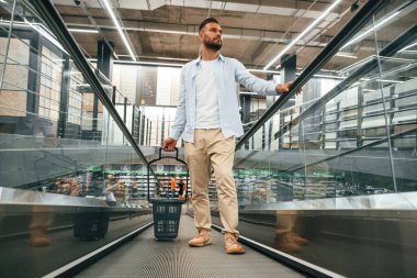 Müşteri gelmek üzeredir. Yakışıklı adam alışveriş merkezindeki yürüyen merdivende..