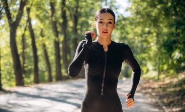 Aktif koşu, koşu. Genç, sıska kadın dışarıda siyah spor kıyafetleri giyiyor..