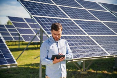 Dijital tablet hazır. Gündüz vakti fotovoltaik güneş panelleri olan bir mühendis..