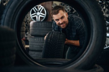 Lastik deliğinden bakıyor. Erkek işçi tekerlekleri olan bakım istasyonudur..